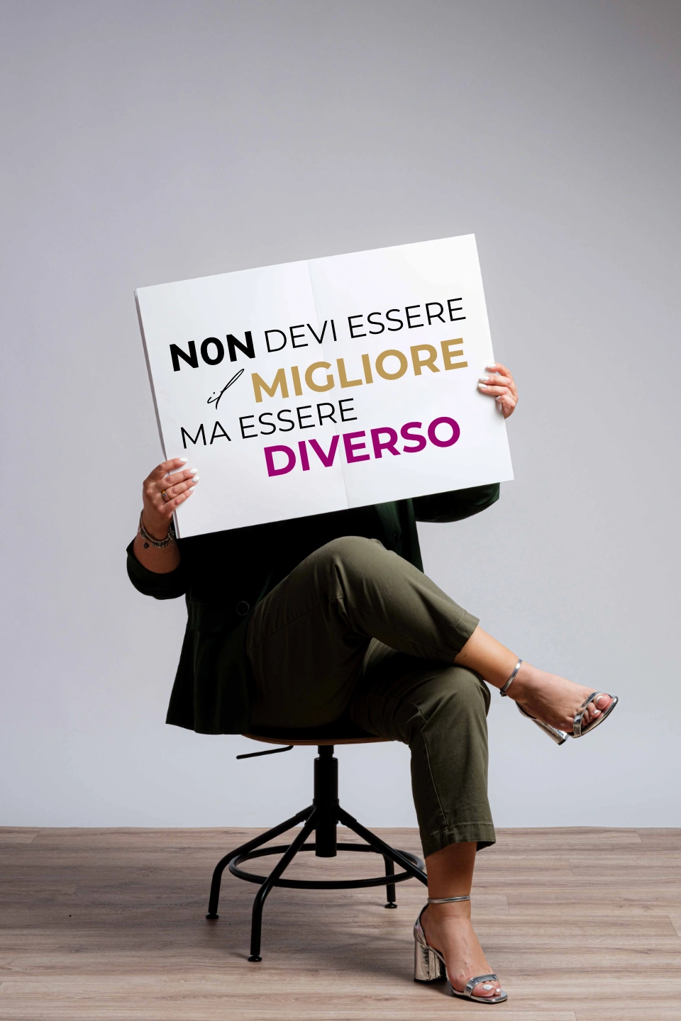 Simina con un cartello riportante la scritta Non devi essere il migliore ma essere diverso